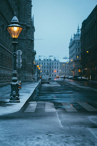 A snow-covered old lantern in the early morning and a street stretching into the distance