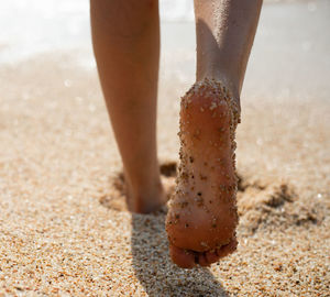 Low section of woman standing on sand at beach