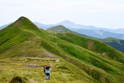 Rear view of hikers walking on mountain against sky