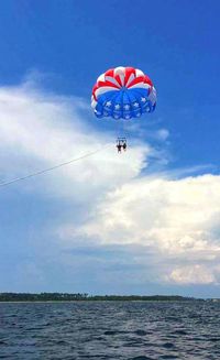 Low angle view of person paragliding against sky