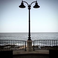 Street light by sea against clear sky