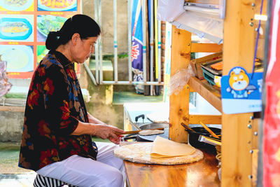 Side view of young woman working in workshop