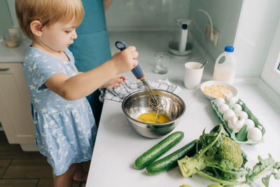 Toddler little daughter helps mom cook dinner.