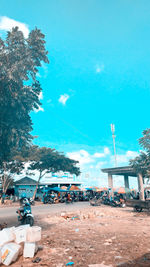 People on street by buildings against blue sky