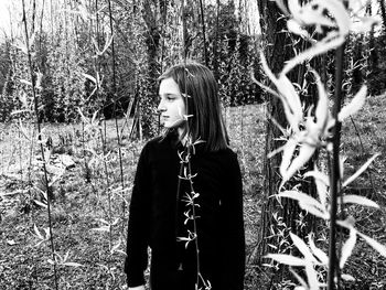 Woman standing by tree on field in forest