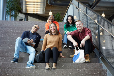 Portrait of smiling students sitting on steps in university