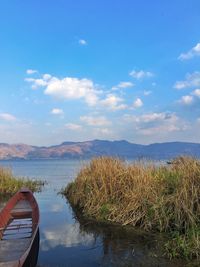 Boat moored in lake against blue sky