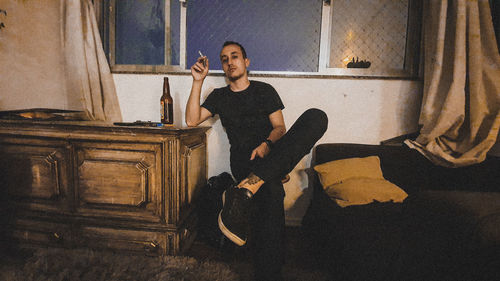 Portrait of young woman sitting on house at home