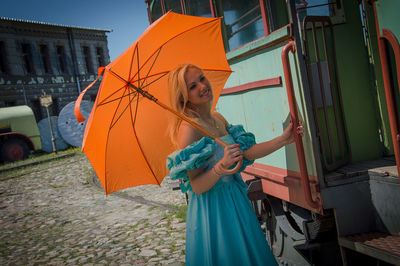 Woman with umbrella standing by old-fashioned tram