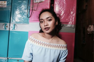 Portrait of young woman standing against wall