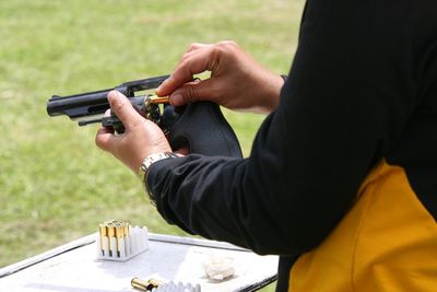 Cropped image of man loading bullets in gun