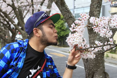 Close-up of man blowing flowers on tree