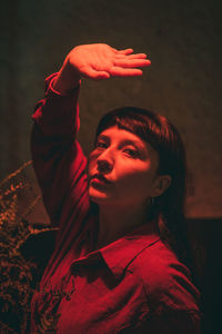 Dark-haired female model in vintage clothing and make-up in a dark bar with red light.