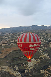 Hot air balloon flying over mountains against sky