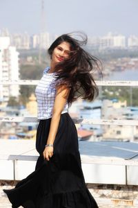 Beautiful young woman standing against cityscape in city