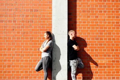 Young woman leaning against brick wall