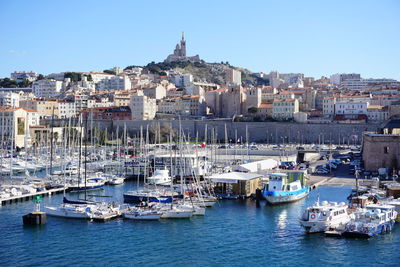 Sailboats moored in harbor against buildings in city