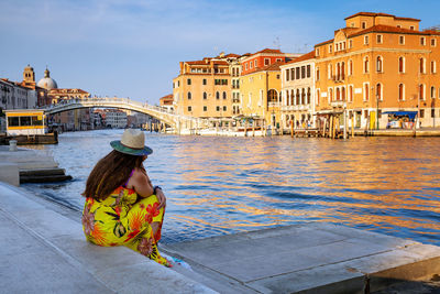 Venice, italy - woman sitting by buildings against sky