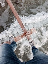 Low section of person standing on wooden structure over river