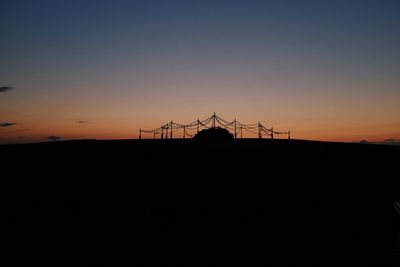 Silhouette yurts on land against sky during sunset