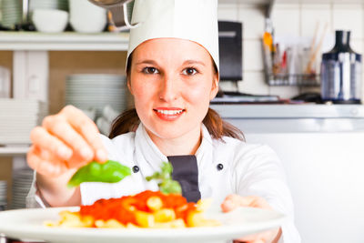 Portrait of smiling young woman eating food in restaurant