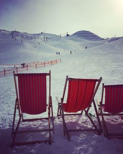 Deck chairs on beach against clear sky