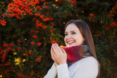 Portrait of a smiling young woman holding autumn leaves