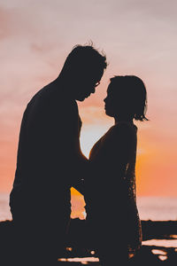 Silhouette couple against orange sky during sunset