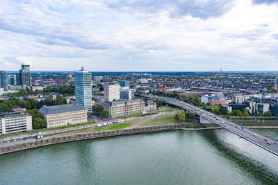 Bridge over river amidst buildings in city against sky
