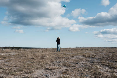 Young boy flying a kite on the top of a hill on a fluffy cloud day