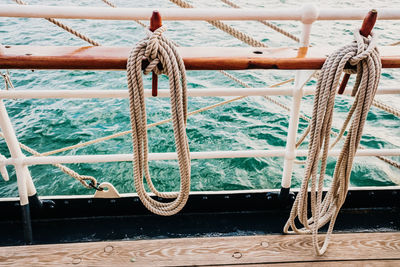 Close-up of rope tied to bollard on railing
