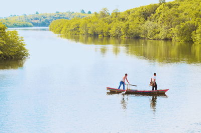 People in boat on lake against trees