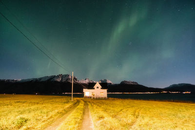 Scenic view of house against snowcapped mountains and northern lights at night
