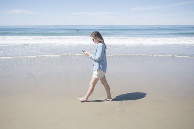 Full length of man standing on beach against sky