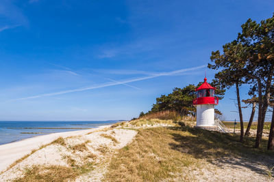 Lighthouse by sea against sky