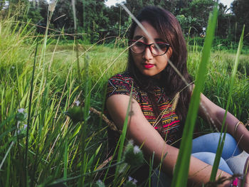 Beautiful young woman sitting amidst grass