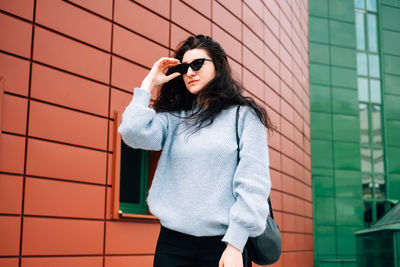 Young woman standing against wall