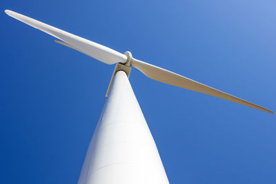 Wind turbine against blue from low angle