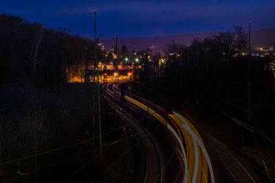 Light trails on railroad tracks against sky at night