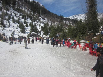 People on snow covered trees against sky