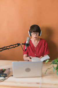 Woman reading book sitting against wall