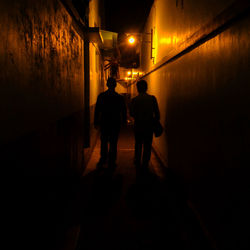 Rear view of silhouette people walking on illuminated wall