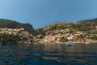 Scenic view of sea and mountains against clear blue sky