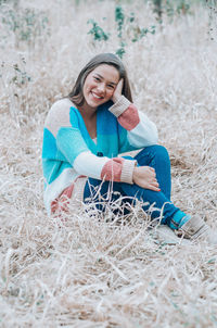 Portrait of smiling young woman sitting on grass outdoors