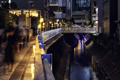 Bridge over illuminated street in city at night