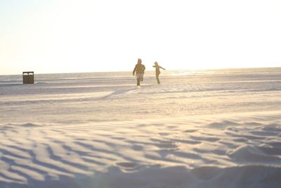 Woman playing on sand at beach against sky during sunset