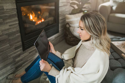 Midsection of woman sitting on sofa at home