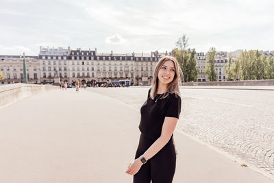 Portrait of smiling woman standing against sky