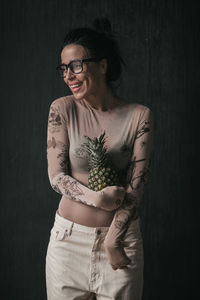 Portrait of smiling young woman standing against black background