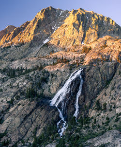 Scenic view of waterfall against rocky mountains